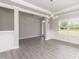 Open dining area featuring gray vinyl floors, white trim, wainscoting and a modern chandelier at 55 Shoreline Dr, Lillington, NC 27546