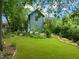 Lush backyard with well-manicured lawn, mature trees, and garden beds, creating a serene outdoor space at 701 Holloway St, Durham, NC 27701