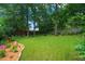 Expansive backyard featuring a lush lawn, mature trees, and decorative flower beds along the fence at 701 Holloway St, Durham, NC 27701