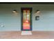 Inviting front porch featuring a red-framed door, vintage sconces, and the house number 