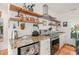 Modern kitchen with stainless steel appliances, stone countertops, stylish open shelving, and wood floors at 701 Holloway St, Durham, NC 27701