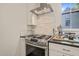 Close-up of a range and stainless appliances in the kitchen with granite counters and marble backsplash at 701 Holloway St, Durham, NC 27701