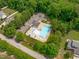 Aerial view showcases a community pool with chairs, umbrellas, and ample parking surrounded by lush trees at 7217 Leando Dr, Willow Springs, NC 27592