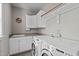 A bright laundry room featuring front-load washer/dryer, white cabinets, and a utility sink at 7217 Leando Dr, Willow Springs, NC 27592