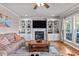 Spacious living room showcasing built-in shelving around a fireplace, a ceiling fan, and hardwood floors at 7217 Leando Dr, Willow Springs, NC 27592