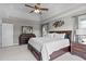 Main bedroom featuring a tray ceiling, ceiling fan, bedside table, and large windows overlooking greenery at 7217 Leando Dr, Willow Springs, NC 27592