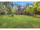Large backyard featuring lush green grass, mature trees, and an outdoor fire pit area at 7529 Tynewind Dr, Wake Forest, NC 27587