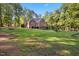 Beautifully landscaped backyard featuring lush green lawn, mature trees, and a brick house at 7529 Tynewind Dr, Wake Forest, NC 27587