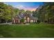 Charming two-story brick home with a lush green lawn and mature trees at sunset at 7529 Tynewind Dr, Wake Forest, NC 27587
