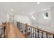 Upstairs hallway with wood floors and a black metal and wood railing and plenty of natural light at 7529 Tynewind Dr, Wake Forest, NC 27587