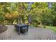 Elegant brick patio featuring a dark gray dining set, umbrella, and lush landscaping at 7529 Tynewind Dr, Wake Forest, NC 27587
