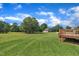 Expansive backyard featuring a wooden deck, lush lawn, mature trees, and a detached garage at 86 Woodall Farm Ln, Princeton, NC 27569
