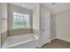 Bright bathroom featuring a soaking tub, separate shower, and a frosted glass window at 86 Woodall Farm Ln, Princeton, NC 27569