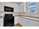 Cozy kitchen showcasing white cabinetry, a window above the sink, and modern black appliances at 86 Woodall Farm Ln, Princeton, NC 27569