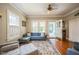 Bright living room with hardwood floors, multiple windows, a ceiling fan, and an exterior door at 1213 Pierce St, Raleigh, NC 27605