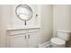 Bathroom with round mirror, toilet, and white sink at 150 Purslane Dr, Franklinton, NC 27525