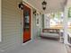Inviting front porch with an orange door, hanging lights, and a relaxing porch swing at 150 Purslane Dr, Franklinton, NC 27525
