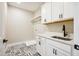 Bright laundry room with white cabinetry, neutral walls, and patterned floor tiling at 150 Purslane Dr, Franklinton, NC 27525