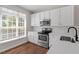 Stylish kitchen featuring white cabinets, stainless steel appliances, and a window view at 1505 Poets Glade Dr, Apex, NC 27523