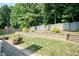 Beautifully landscaped backyard featuring a stone retaining wall, manicured lawn, and privacy fence at 212 Mickleson Ridge Dr, Raleigh, NC 27603