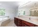 Bright bathroom featuring double sinks, vanity, soaking tub, large mirror, and walk in shower at 212 Mickleson Ridge Dr, Raleigh, NC 27603