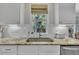 Bright kitchen featuring a stainless steel sink and granite countertop, with a window view of lush greenery at 213 N Weststone Blvd, Fuquay Varina, NC 27526