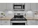 Modern kitchen features stainless steel appliances, including a range, microwave, and white cabinetry at 213 N Weststone Blvd, Fuquay Varina, NC 27526