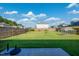 A spacious backyard with a lush lawn, wood fence, and small greenhouse at 217 Windy Knoll Dr, Graham, NC 27253