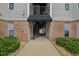 Exterior view of building with red brick and tan siding, stairs leading up, and a black awning at 2521 Friedland Pl # 303, Raleigh, NC 27617