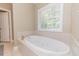 Bathroom features a soaking tub, tile surround, jetted tub, and a large window with shades at 26 Shadymont Dr, Pittsboro, NC 27312