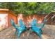 Backyard patio with gravel, blue Adirondack chairs around a fire pit, and a mature privacy hedge at 309 E End Ave, Durham, NC 27703