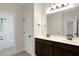 Double vanity bathroom with dark cabinets, a large mirror, and a door to the shower at 315 Sugarpine Trl, Clayton, NC 27520