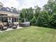 Backyard patio features a hot tub, seating, and landscaped yard with a wooded view at 3441 Jordan Shires Dr, New Hill, NC 27562