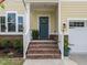 Inviting entrance featuring brick stairs, a blue front door adorned with a wreath, and potted plants at 3441 Jordan Shires Dr, New Hill, NC 27562