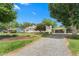 View of a home featuring mature landscaping and a gravel driveway leading to a carport at 409 Trail Two, Burlington, NC 27215