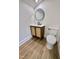 Cozy bathroom with wood-look flooring, stylish vanity, round mirror and new toilet at 41 Lakewood Dr, Roxboro, NC 27573