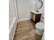 Cozy bathroom with wood-look flooring, stylish vanity, round mirror and new toilet at 41 Lakewood Dr, Roxboro, NC 27573
