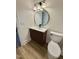 Bathroom featuring a round mirror over a modern vanity, wood-look floors and a white toilet at 41 Lakewood Dr, Roxboro, NC 27573
