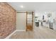 Open dining area with brick accent wall and sliding barn door leading to the modern kitchen at 7722 Nc 27, Lillington, NC 27546