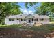 Charming brick ranch home with a new roof and black shutters surrounded by mature trees at 7722 Nc 27, Lillington, NC 27546