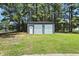 A two car metal garage, with two garage doors, surrounded by trees, is an excellent additional parking and storage solution at 7722 Nc 27, Lillington, NC 27546