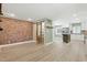 Spacious living room featuring a brick accent wall and an open-concept layout to the modern kitchen at 7722 Nc 27, Lillington, NC 27546