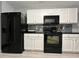Modern kitchen featuring white cabinets, black appliances, and stylish blue-grey backsplash at 8836 Thornton Garden Ln, Raleigh, NC 27616