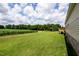 Lush green backyard with a partial view of the deck and surrounding greenery at 100 Cottonwood Ct, Kenly, NC 27542