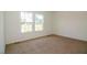 Empty bedroom featuring tan carpet and two windows with backyard view at 100 Cottonwood Ct, Kenly, NC 27542