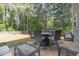 Cozy outdoor patio with wicker furniture and dining set, surrounded by lush trees and a fenced yard at 115 Baystone Dr, Sanford, NC 27332