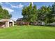 Large backyard view of brick home with green grass, storage shed, and mature trees at 201 N Us 301, Micro, NC 27555