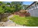 Landscaped backyard with a wooden deck, stone walkway, and lush green lawn at 2020 Port Royal Rd, Raleigh, NC 27609