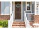 Close-up of the front door with a decorative wreath, brick steps, and charming details at 210 Olde Liberty Dr, Youngsville, NC 27596