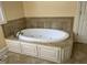 Bathroom featuring a large soaking tub with tile surround and white cabinetry at 211 Hillcrest Dr, Oxford, NC 27565